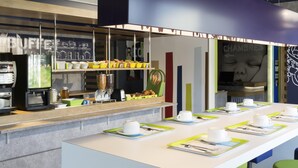 A modern cafe with a long counter, coffee machines, and a variety of food items displayed on shelves. - ibis Budget Lyon Eurexpo Chassieu (Chassieu)