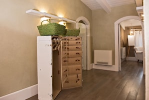 Un pasillo con un mueble blanco de almacenamiento, cajones de madera y una cesta encima.