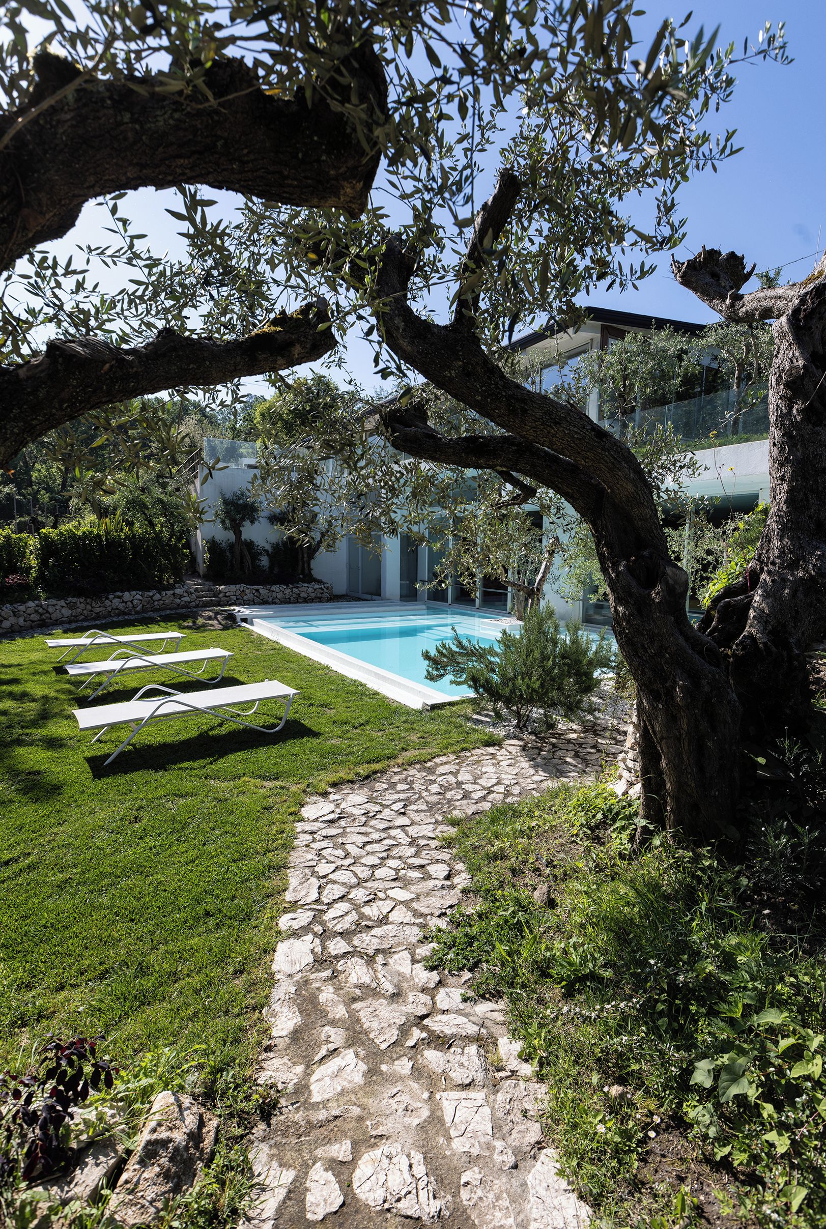 Un sendero de piedra que conduce a una piscina con vistas a un edificio y árboles.
