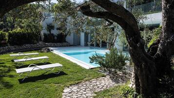 Un sendero de piedra que conduce a una piscina con vistas a un edificio y árboles.