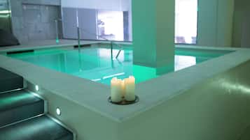 A swimming pool with a greenish tint, a candle on a ledge, and a staircase leading down.