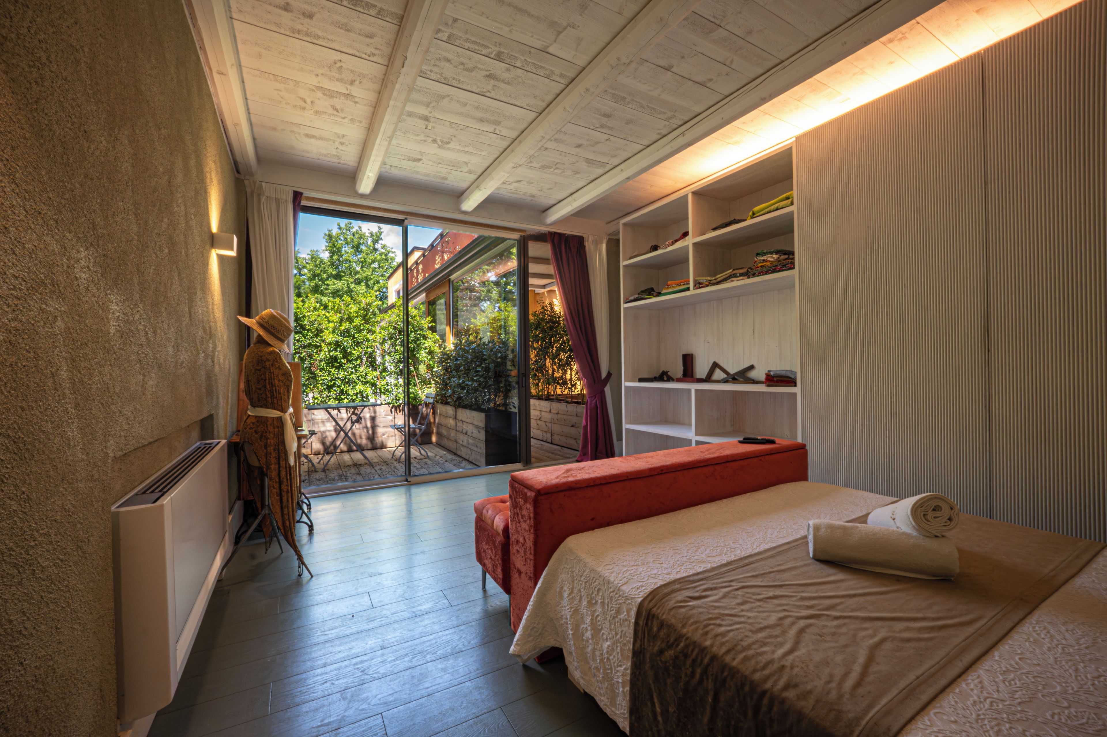 Ein Schlafzimmer mit großem Fenster, einem Bett, einem Kleiderschrank und einem kleinen Balkon.
