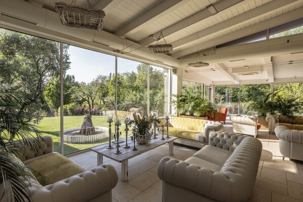 Un luminoso solárium amplio con ventanas grandes, un espacio de estar confortable con sofás y una mesa de centro, y vistas al jardín exterior.