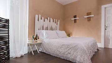 Un dormitorio con una cama grande, una mesita de noche con lámpara y una estantería de pared.