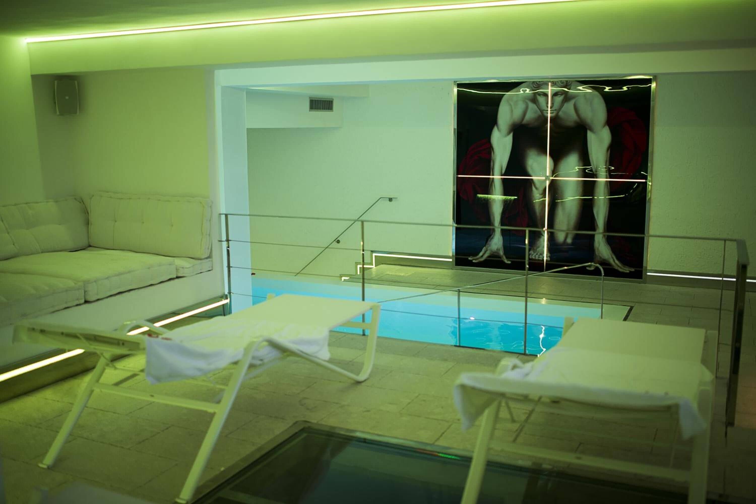 Un espace piscine avec des chaises longues et une grande affiche représentant une silhouette musclée sur le mur.