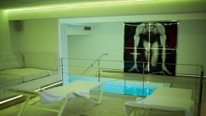 A swimming pool area with lounge chairs and a large poster of a muscular figure on the wall. - La Pampa Relais (Melizzano)