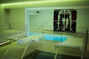 Zona de piscina con sillones de descanso y un cartel grande de un hombre musculoso en la pared.