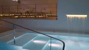 A modern indoor pool area with a glass barrier and a waterfall feature. - La Pampa Relais & Spa (Melizzano)