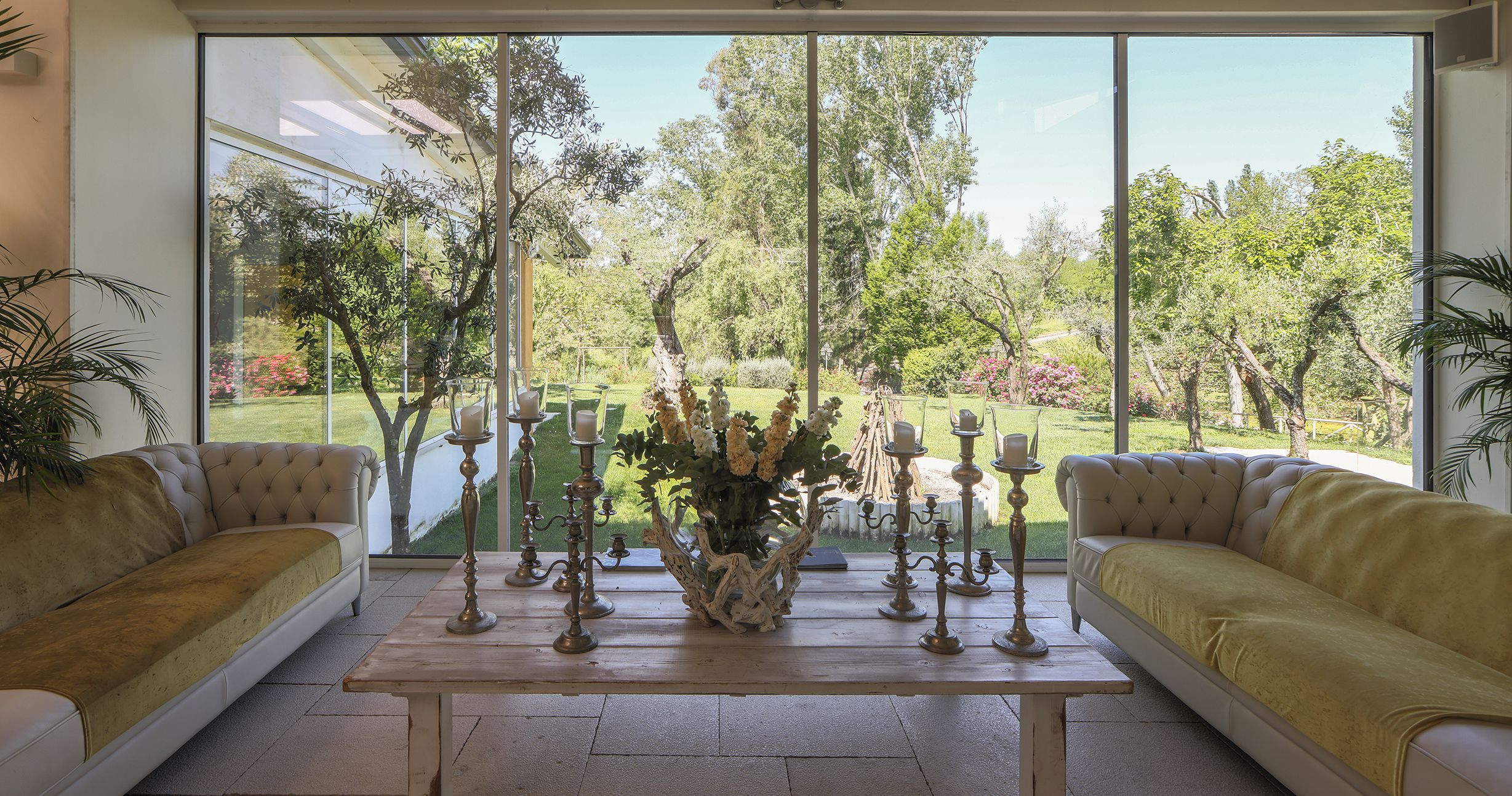 Una stanza con due divani rivolti verso una grande finestra con vista su un giardino.