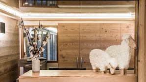Un interior de madera con un mostrador de recepción, un jarrón con flores secas y dos esculturas de ovejas blancas.