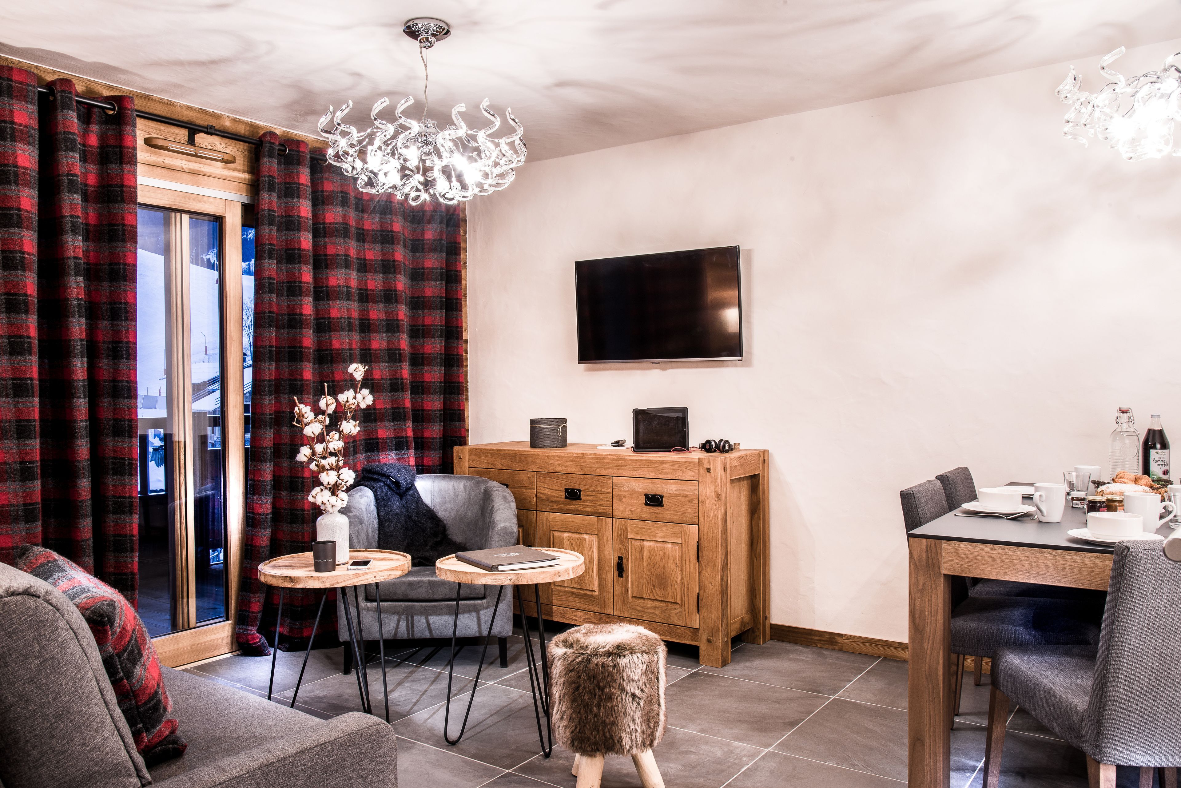 Un salon chaleureux avec un canapé, une petite table ronde, un meuble en bois et un coin repas comprenant une table et des chaises.