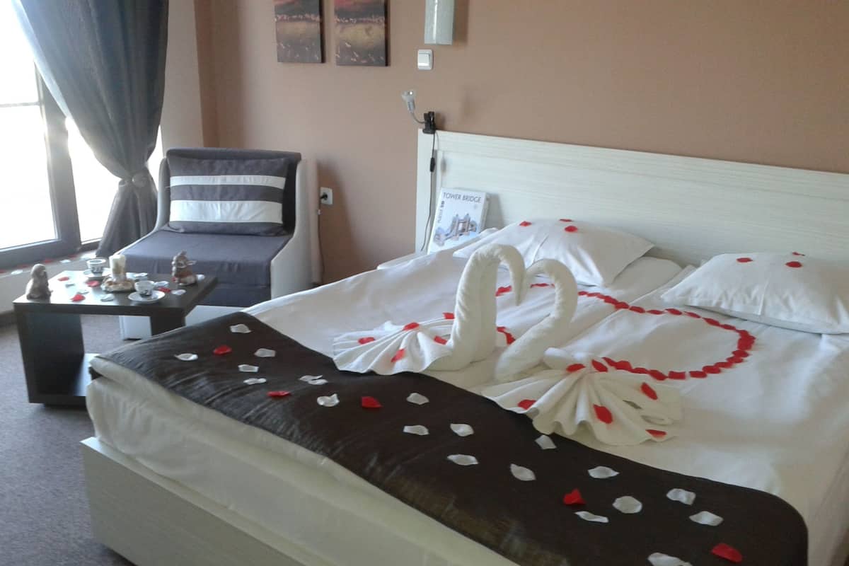 A neatly made bed with a decorative swan design, a bedside table with a figurine, and a chair.