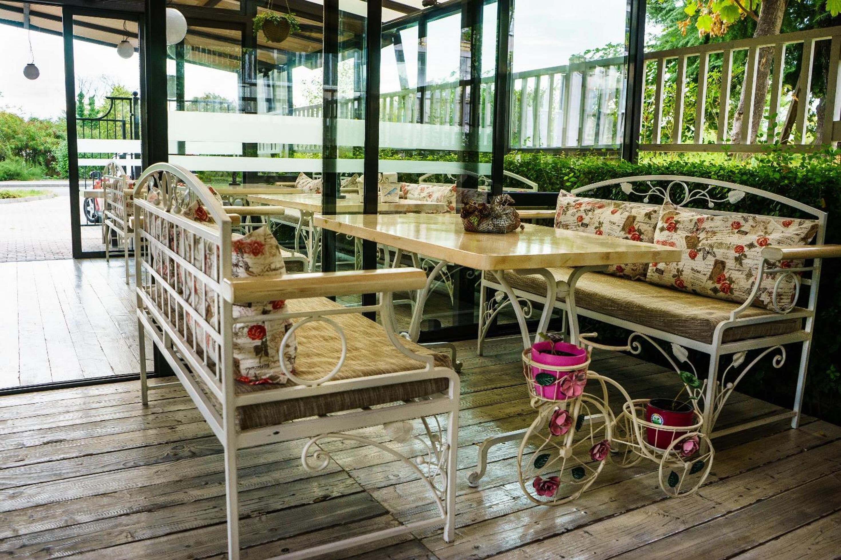 Un patio al aire libre con suelo de madera, mobiliario metálico y una valla blanca al fondo.