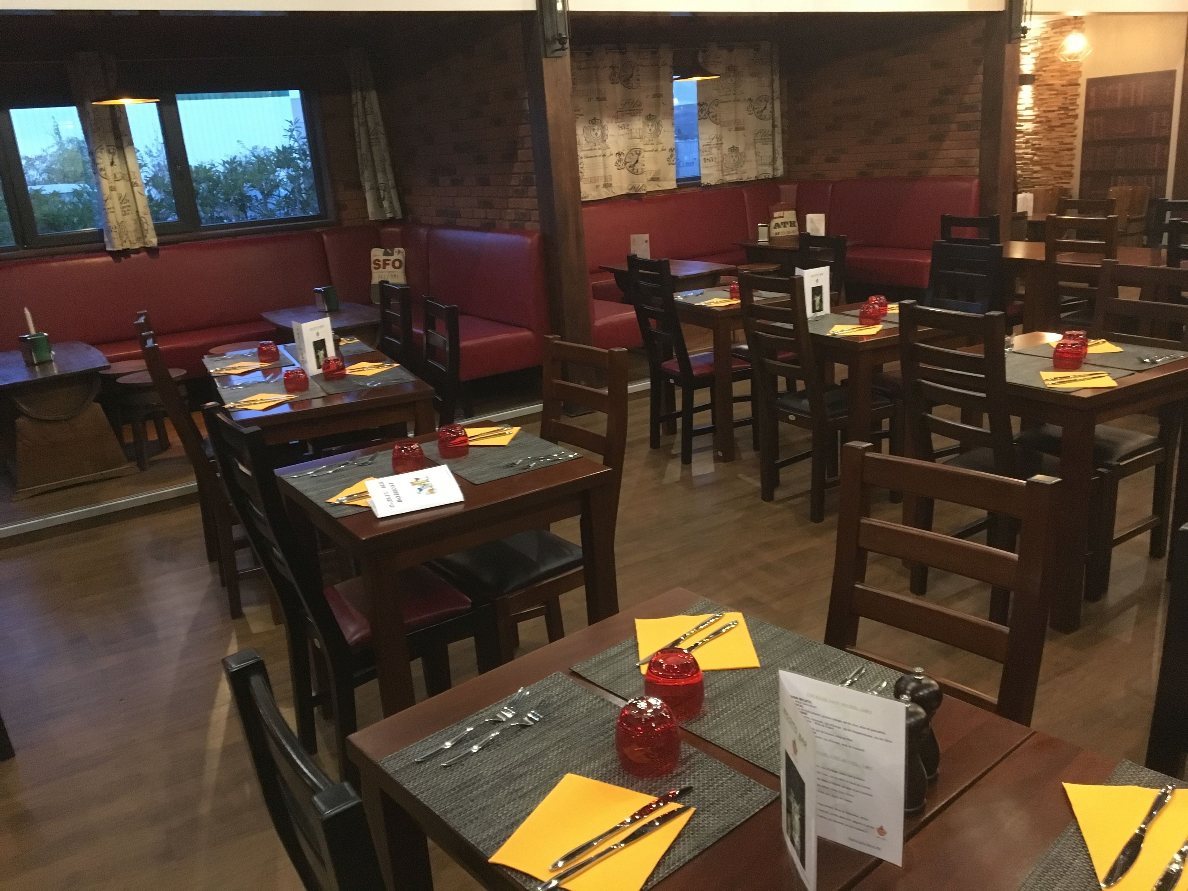 A restaurant with wooden tables and red cushioned seating.