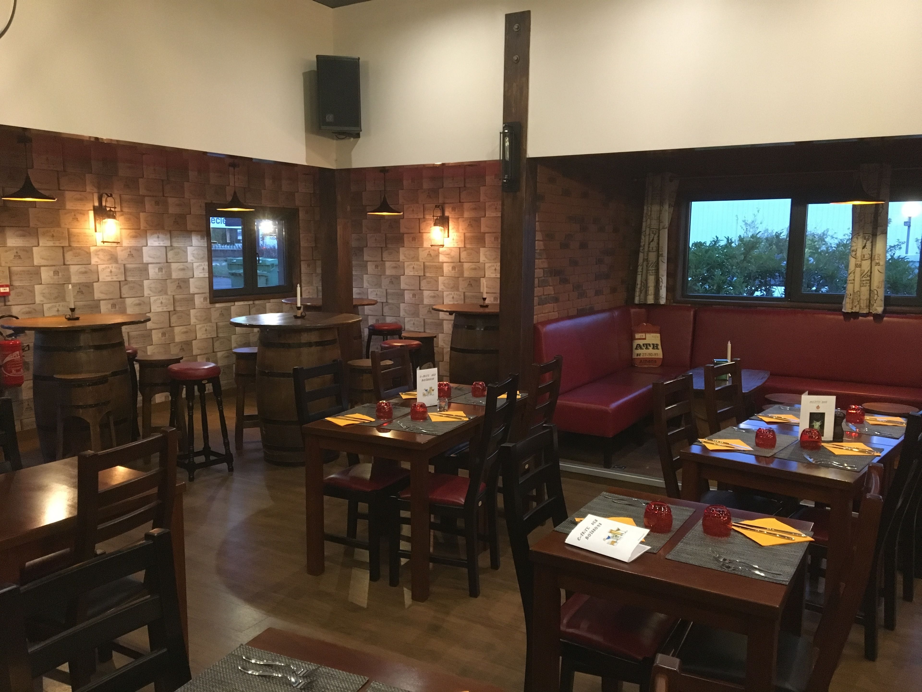 Un restaurante con mesas y sillas de madera, un muro de ladrillo y un sofá rojo.