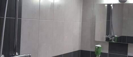 Un baño moderno con ducha, lavamanos y toallero.
