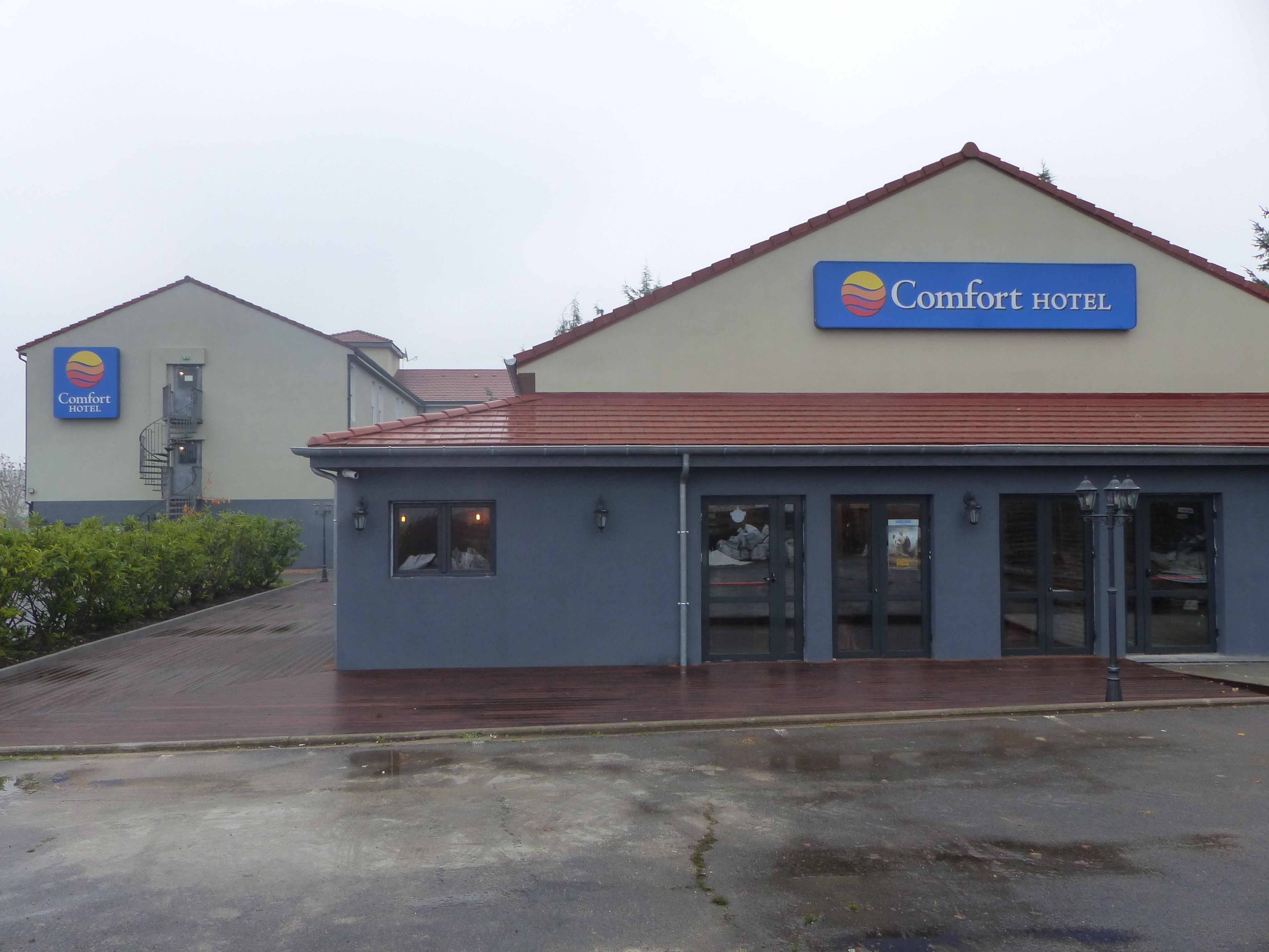 A Comfort Hotel building with a red roof and a blue sign.