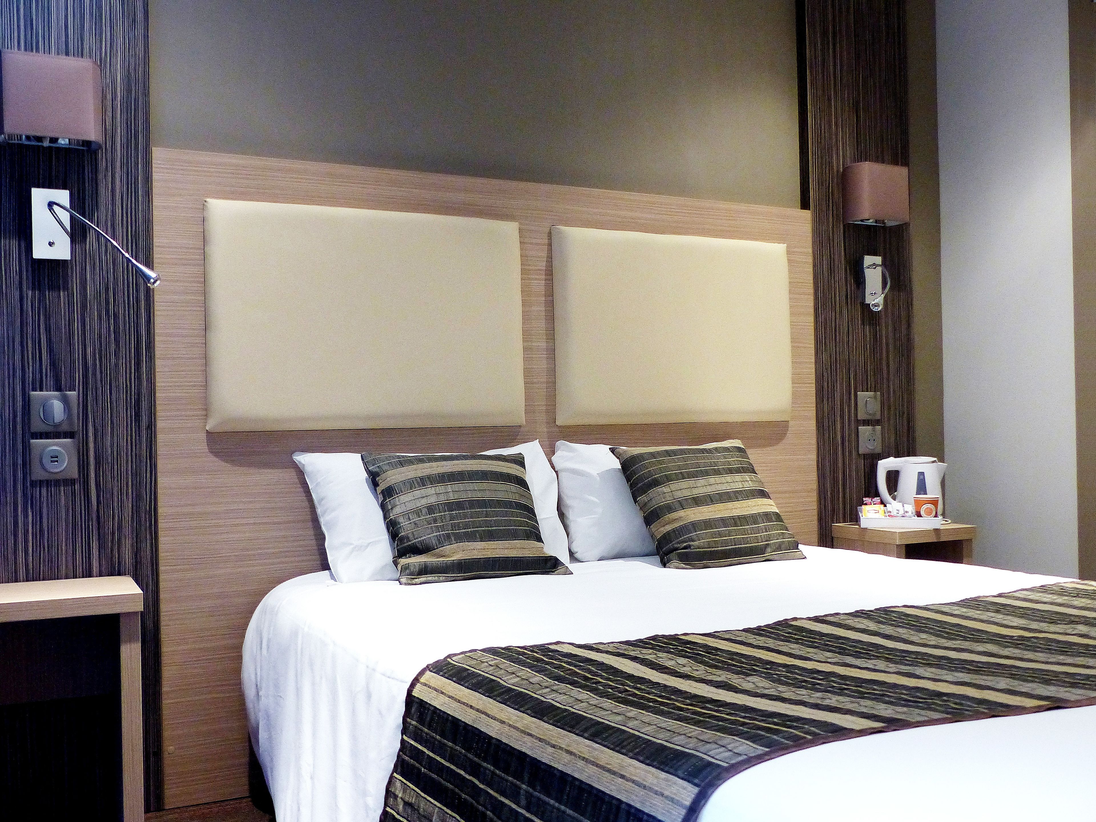 Een hotelkamer met een groot bed, twee nachtkastjes en een nachtkastje met een koffiezetapparaat.