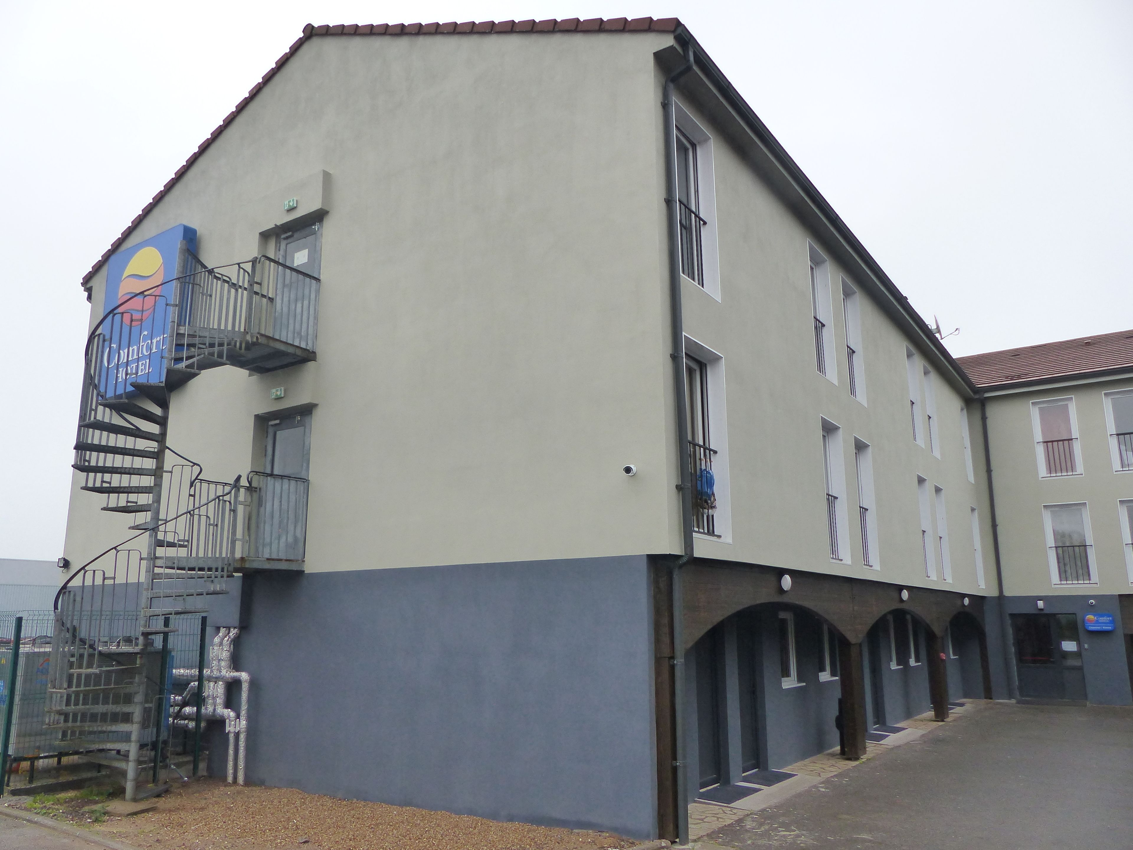 A building with a blue and white facade, a visible staircase, and multiple windows.