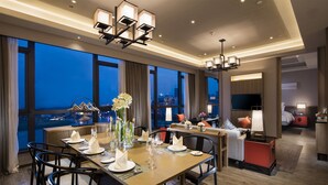 A modern hotel dining area with a large table set for a meal, a city view, and a cozy seating area with a TV. - Pullman Hefei Sunac (Hefei)