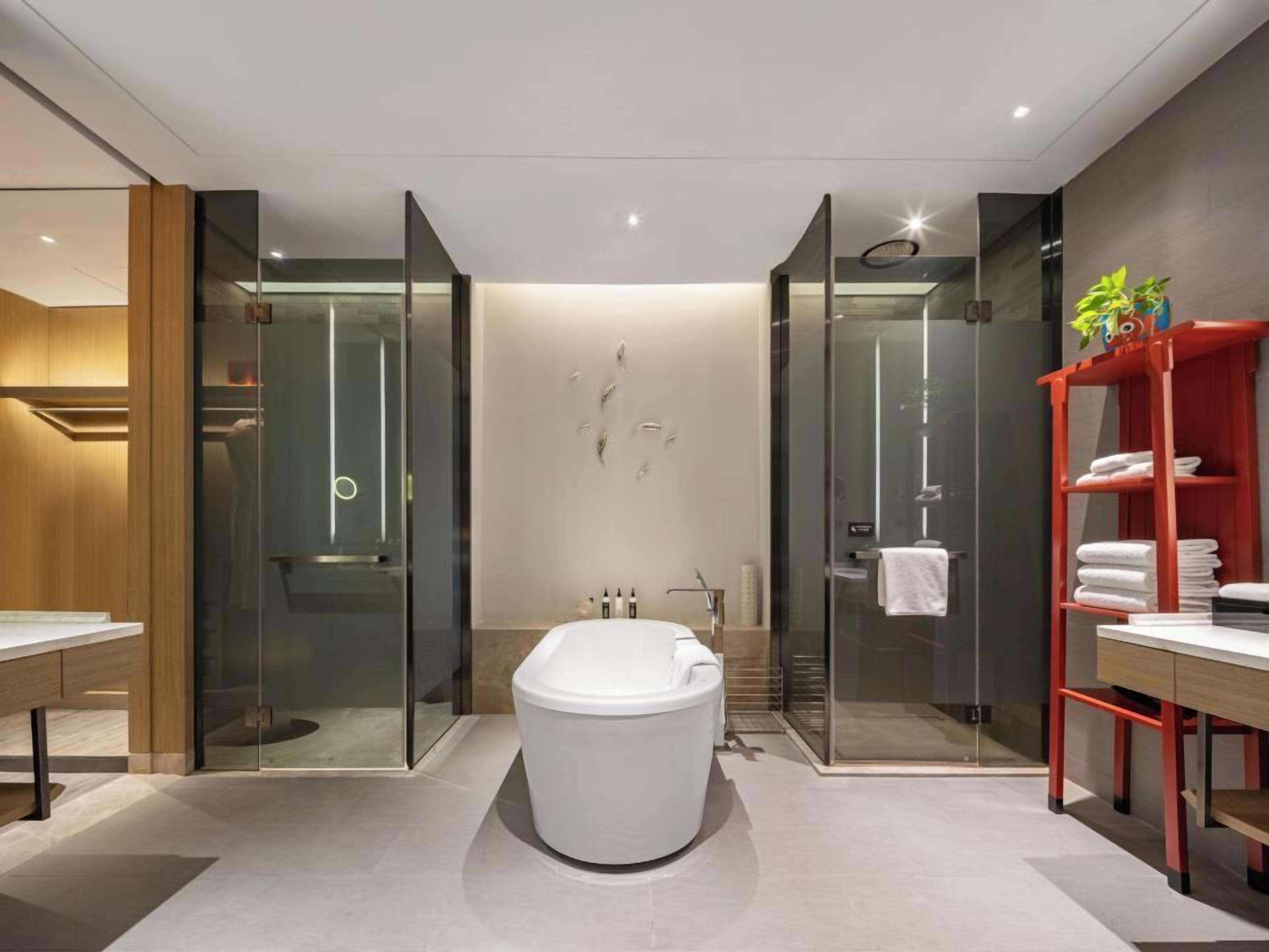 Un baño moderno con cabina de ducha de vidrio, inodoro blanco y un perchero rojo.