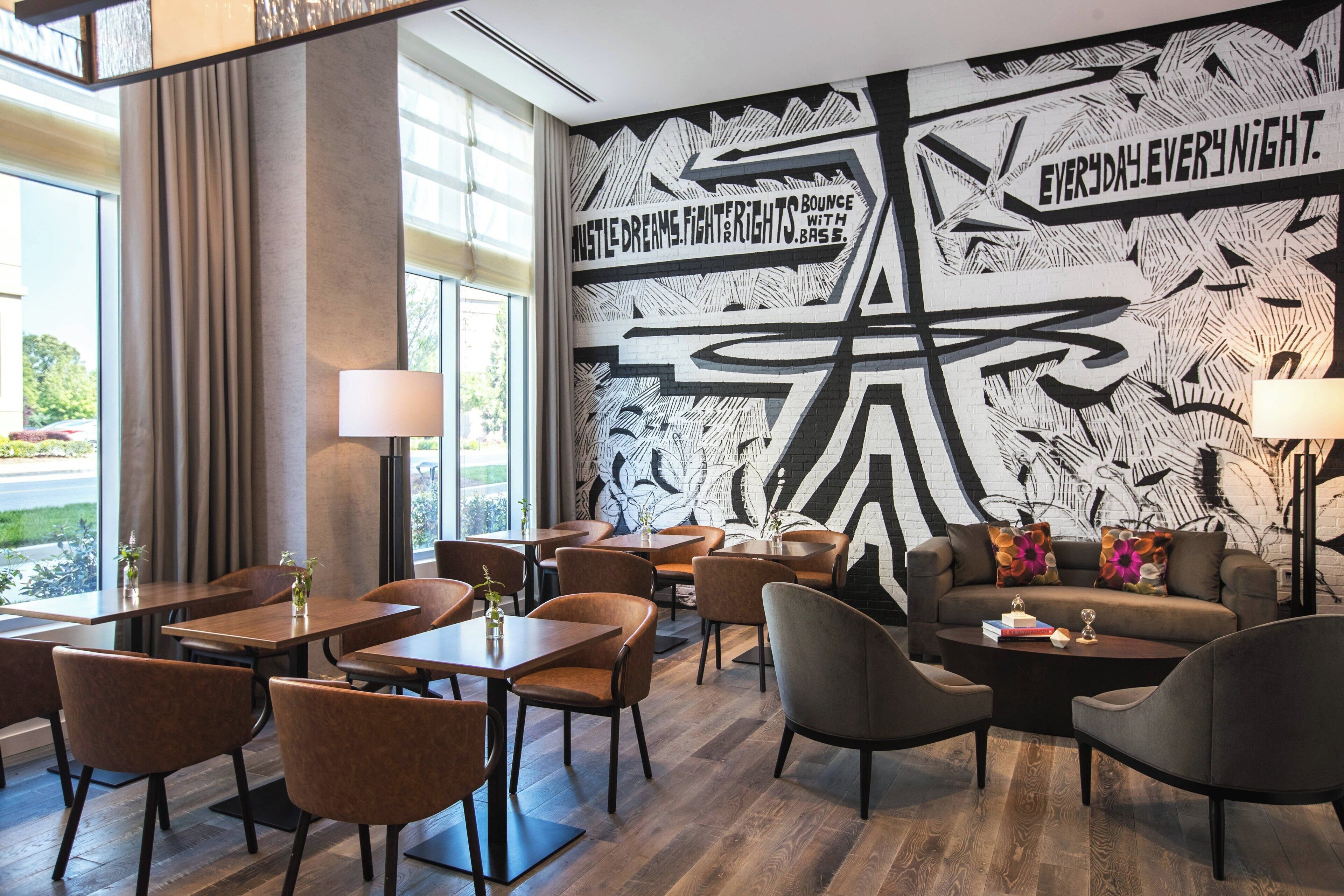 A modern lounge area with a large mural, comfortable seating, and a view of the outdoors.