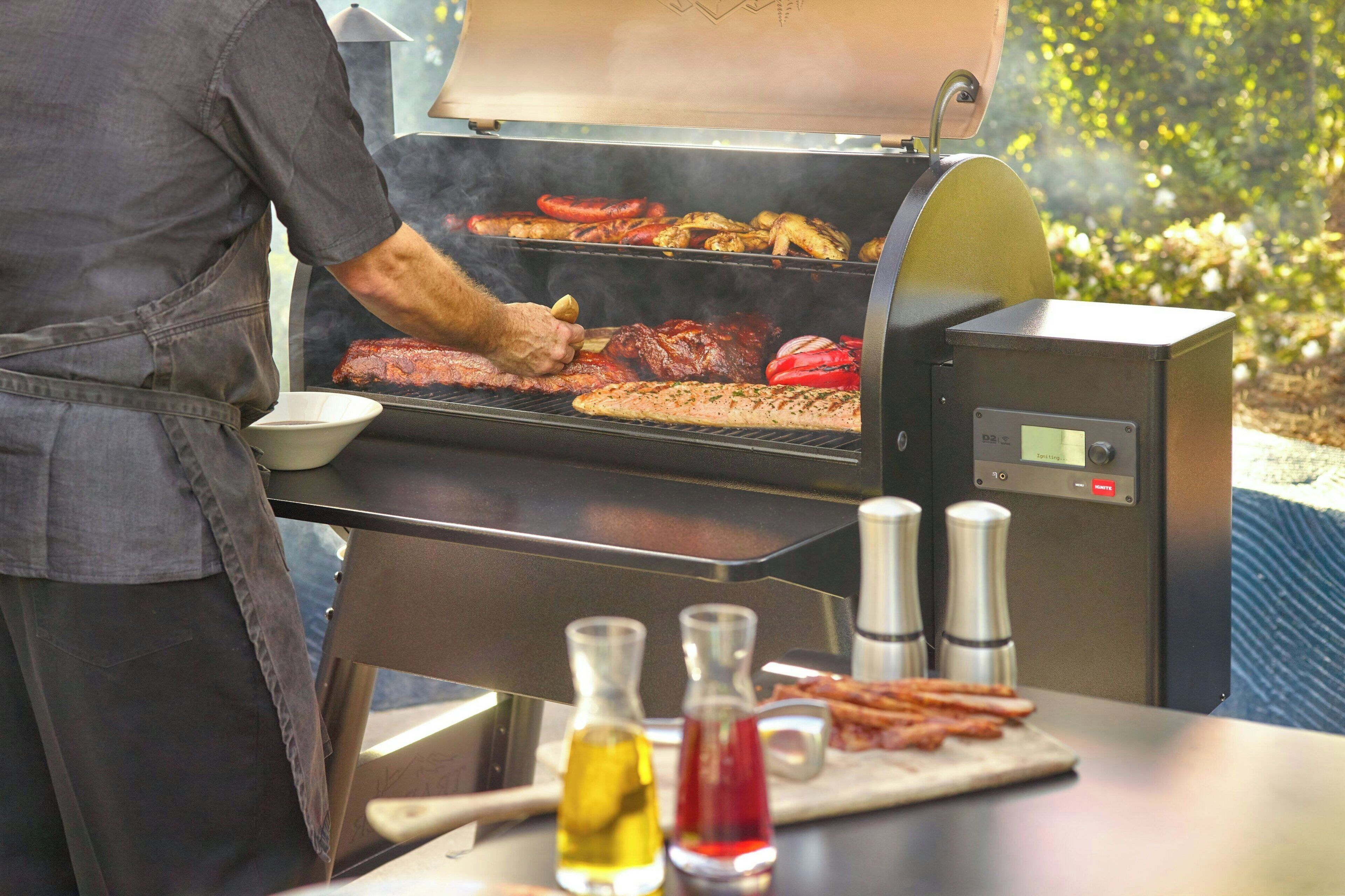 A person grilling various meats on an outdoor grill.
