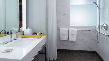 Un baño moderno con un espejo grande, dos lavamanos, una ducha y un perchero para toallas.
