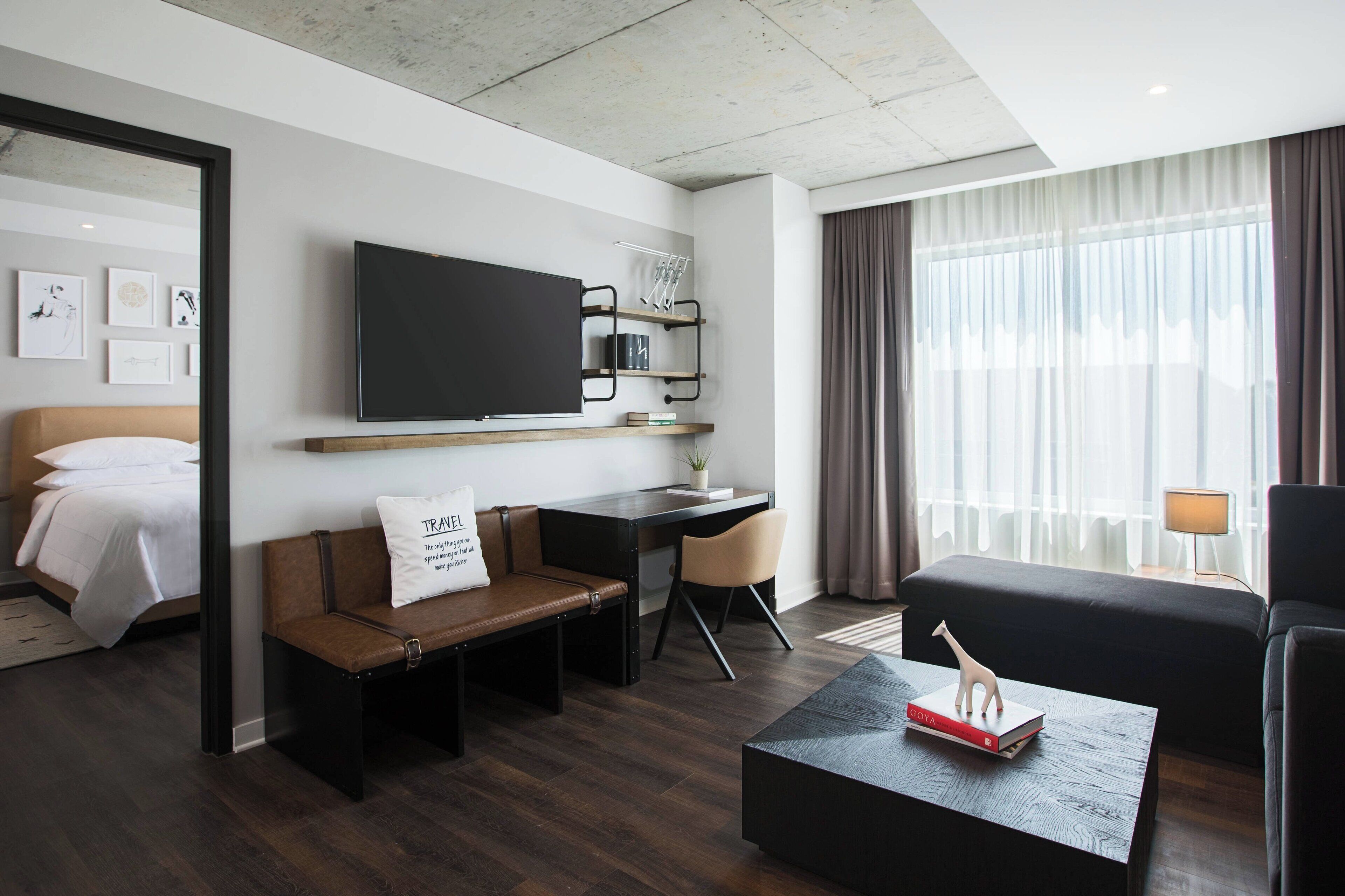 Una habitación de hotel moderna con cama, sofá, escritorio y televisor.