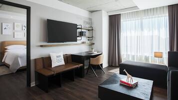 Una habitación de hotel moderna con cama, sofá, escritorio y televisor.