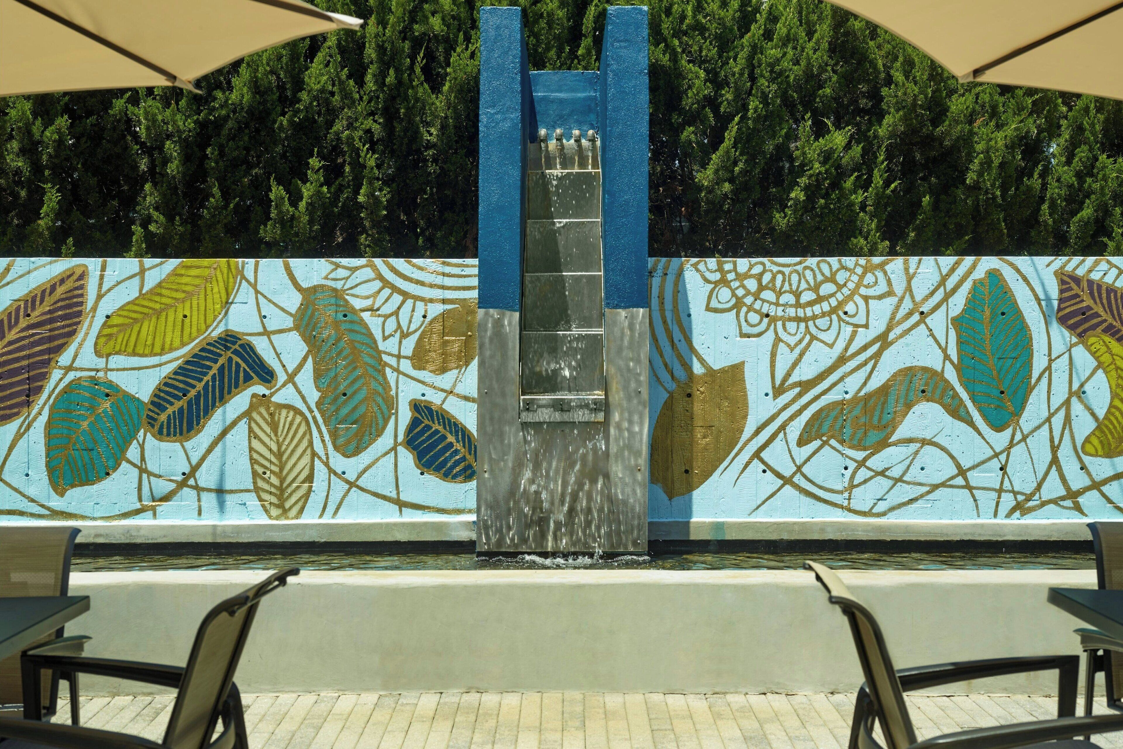 Una fuente con una estructura azul y un mural con motivos de hojas.