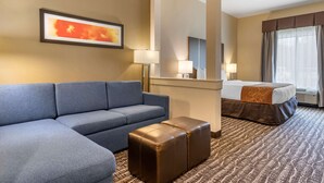 Een hotelkamer met een bank, een klein voetenbankje, een bed, een spiegel en een raam met gordijnen.