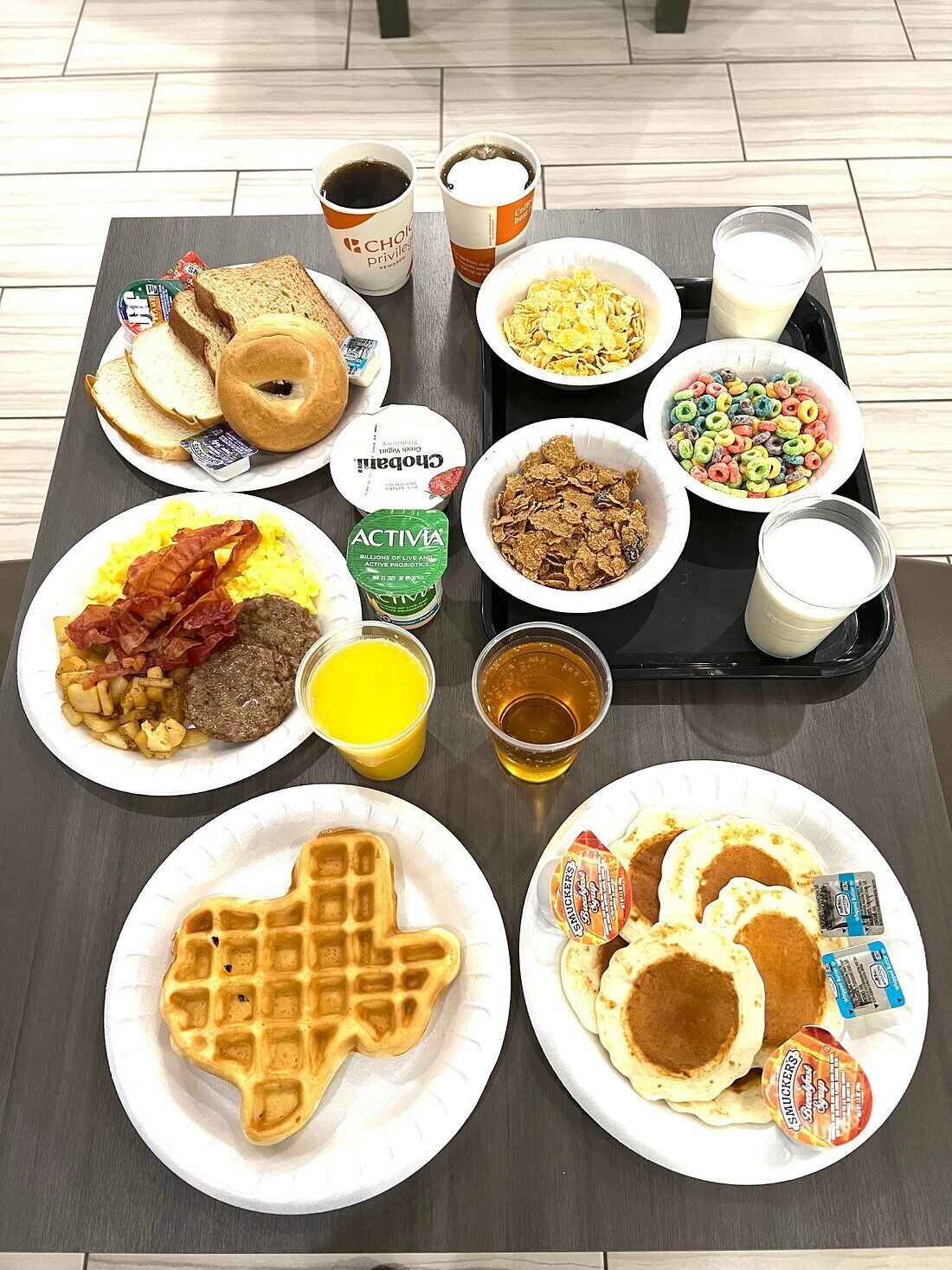 Een ontbijtkar met diverse producten, zoals wafels, pannenkoeken, eieren, spek en cornflakes.