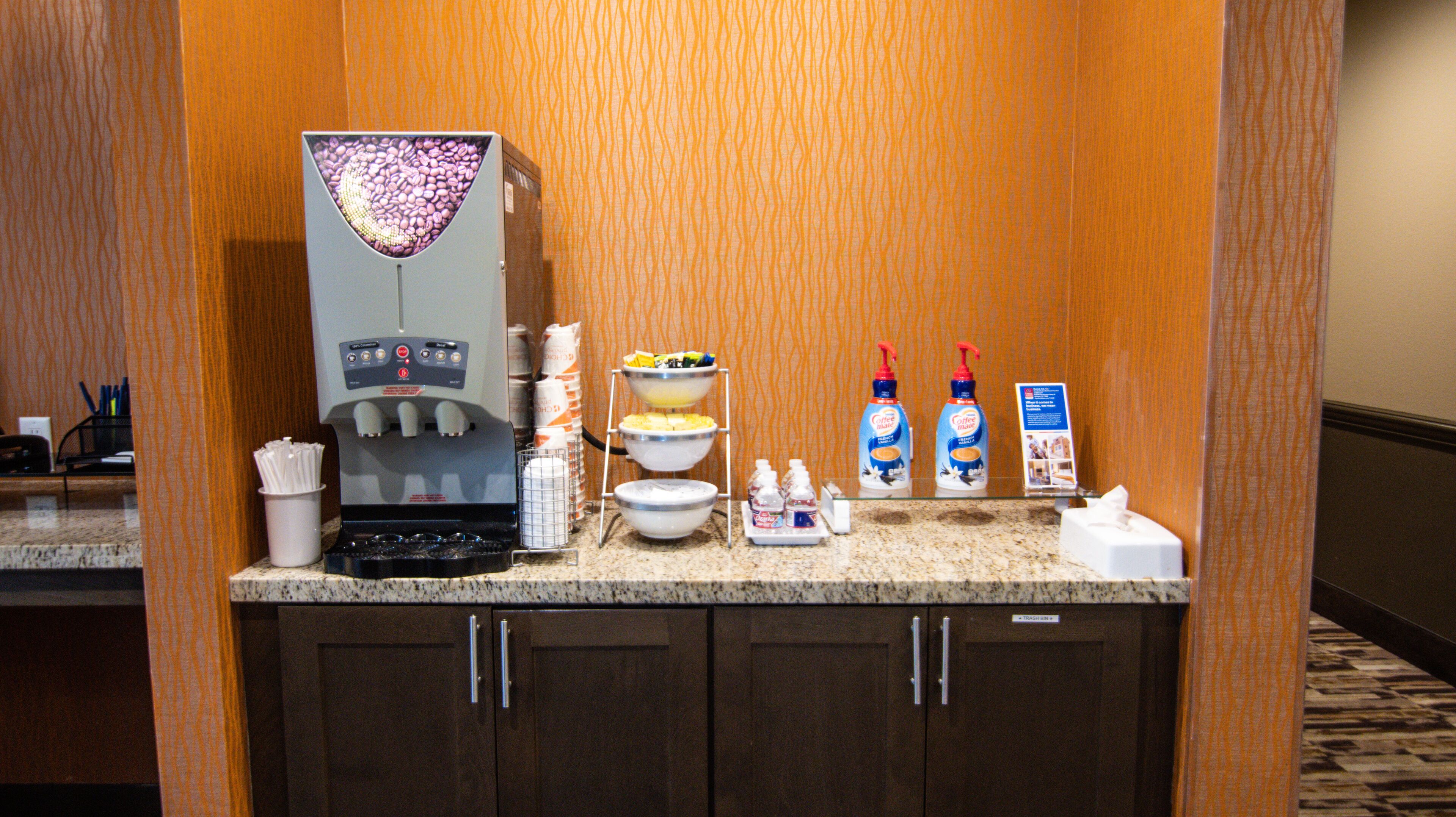 Een hotelkeuken met een koffieapparaat, kommen met eten en kruiden.