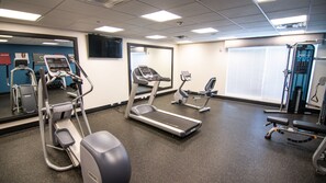 Un centre de remise en forme équipé de tapis de course, de vélos elliptiques et d'appareils de musculation.