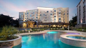 Un hotel con piscina, mobiliario exterior y una entrada bien iluminada.