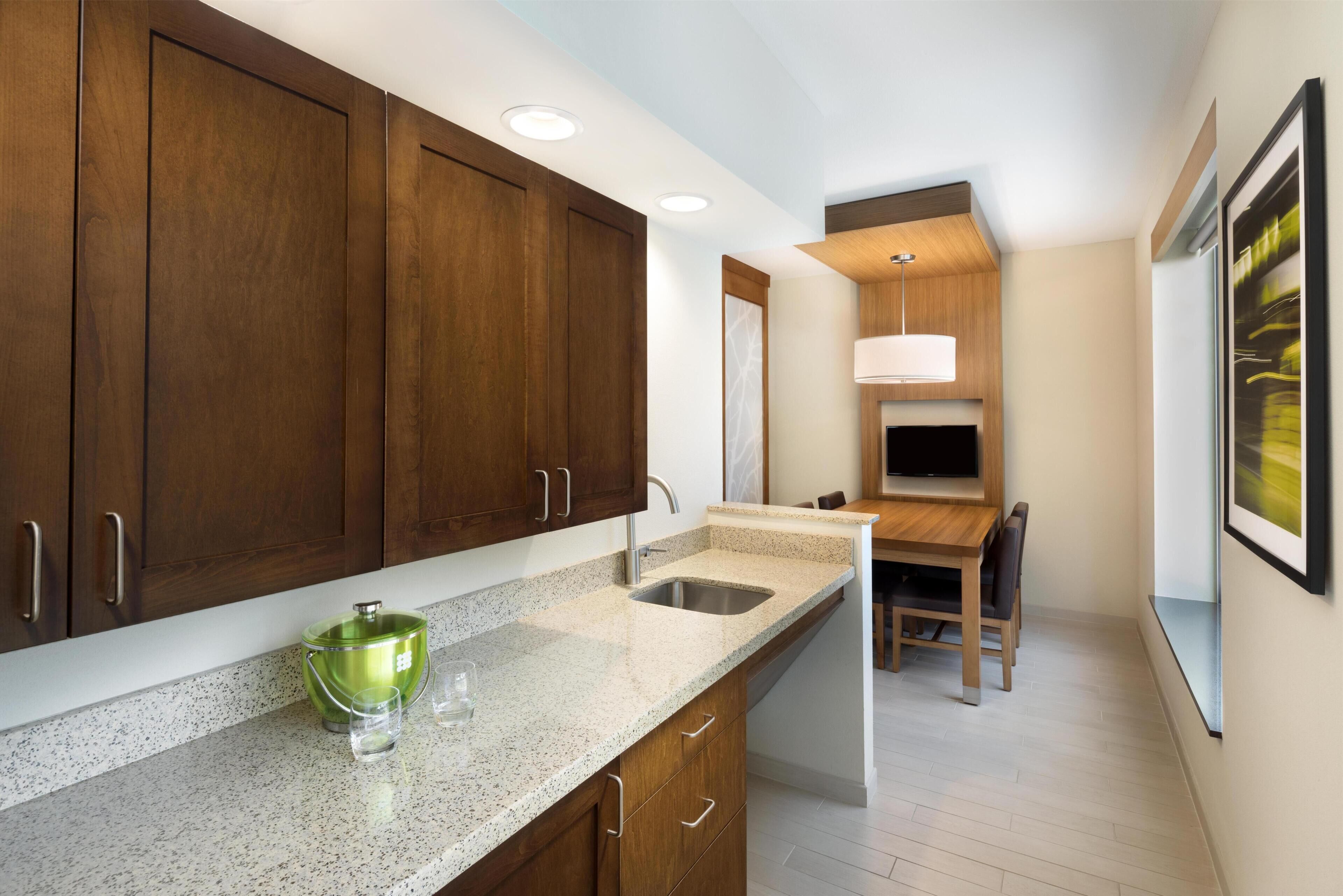 A modern kitchen with wooden cabinets, a granite countertop, and a built-in sink.