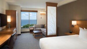 Habitación de hotel con cama, escritorio, televisor, sofá y vista al océano.
