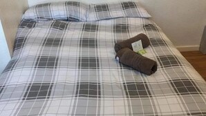 A bed with a plaid bedspread and two folded brown socks on it. - Nelcon Hotel (Blackpool)