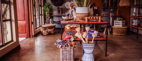 A cozy room with a wooden floor, a table with various items, a wicker basket, and a vase with dried plants.