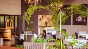 Een restaurant met rieten meubels, een houten vat en decoratieve muurkunst.