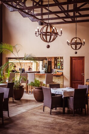 A restaurant with wicker chairs, a bar area, and a wooden ceiling. - Bushveld Terrace Safari Hotel, Lodge & Spa (Phalaborwa)