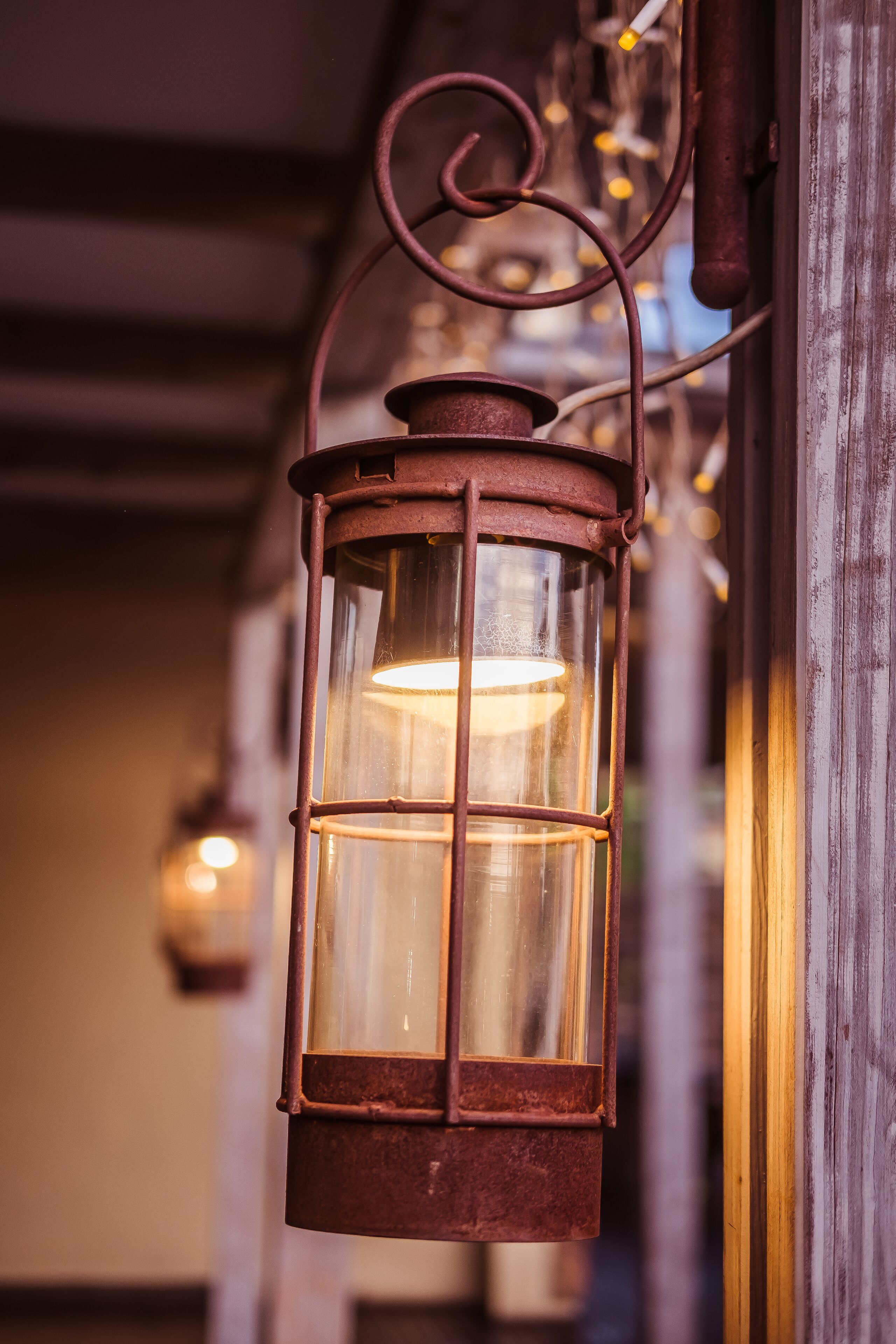Un farol rústico de metal colgado de una viga de madera, con una luz cálida en su interior.