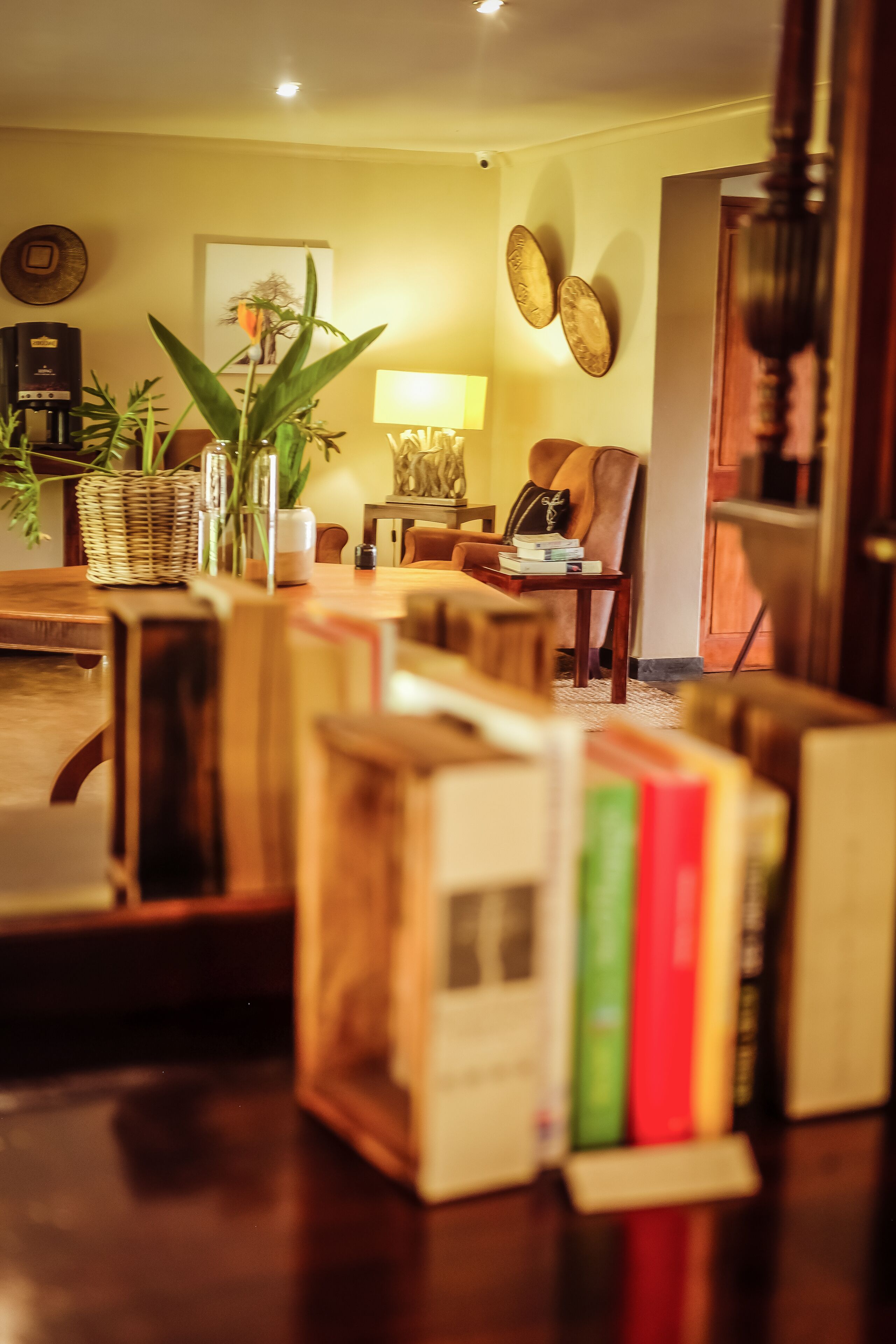 Ein gemütliches Wohnzimmer mit Couchtisch aus Holz, einer Bücherablage, einer Lampe und einem Sessel.