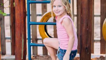 Children can climb and play in the outdoor play area with a wooden structure and ladder.