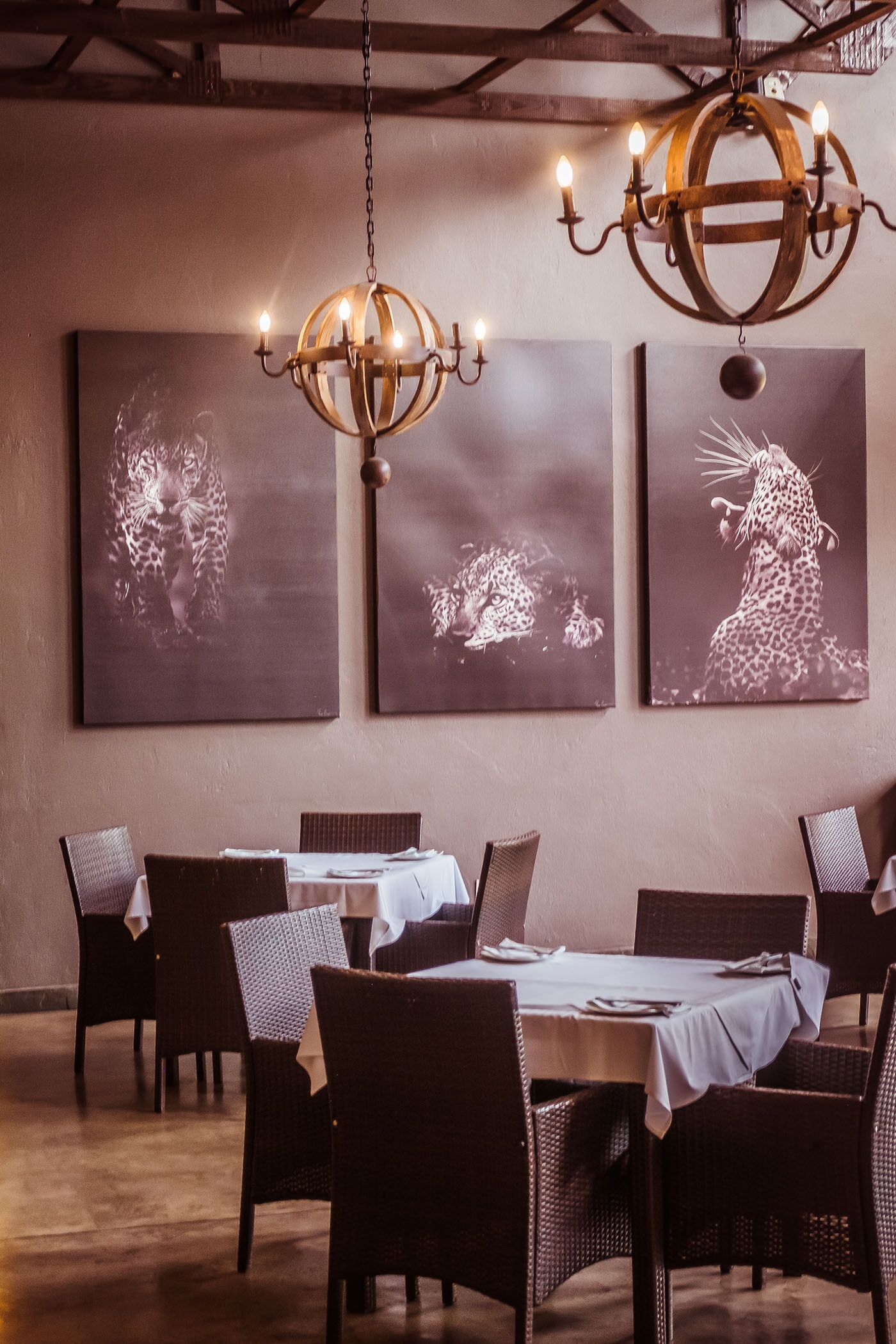 Zona pranzo con un lampadario, sedie in vimini e opere d'arte alle pareti.