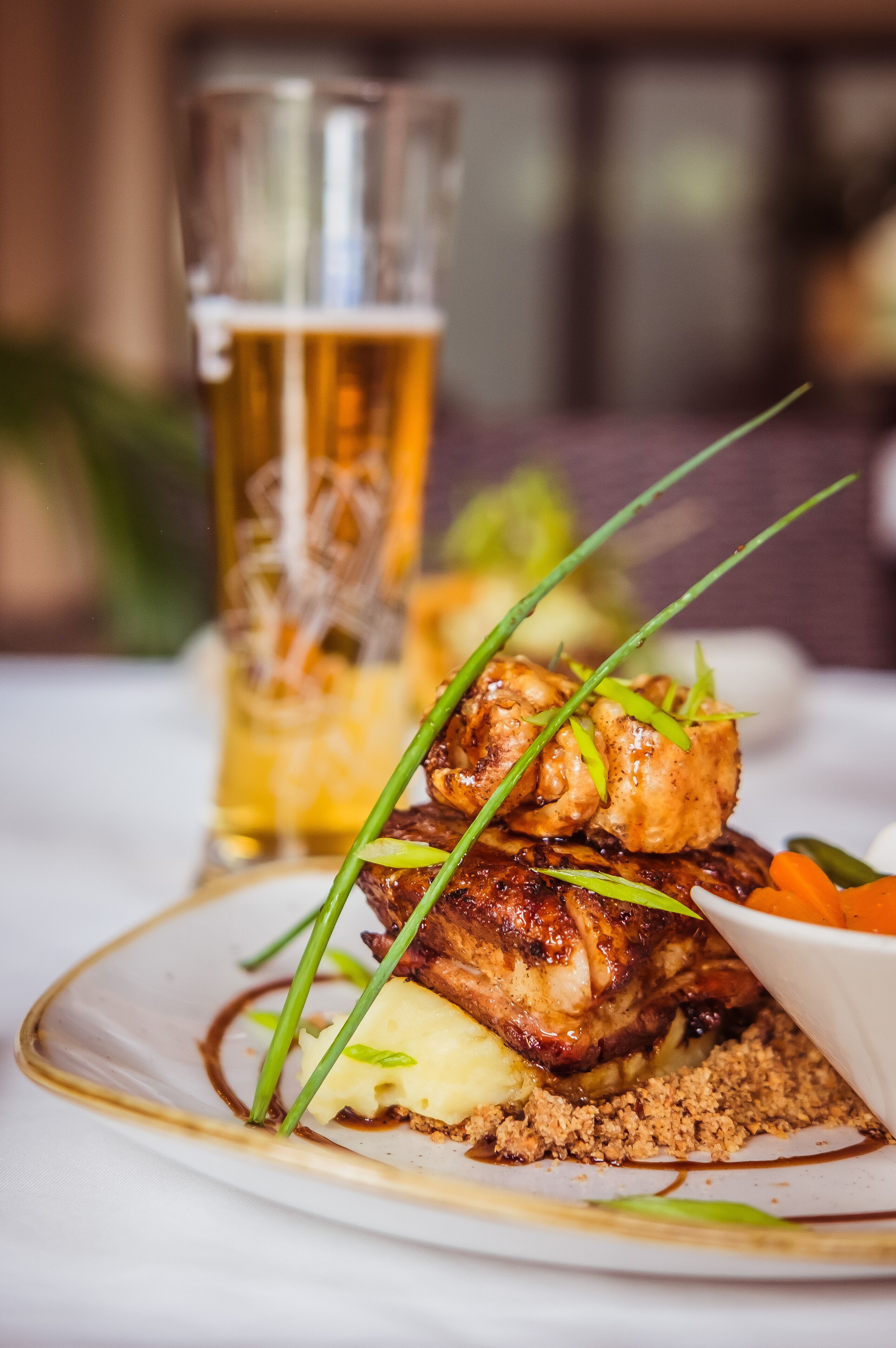 A plate of food with a glass of beer in the background.