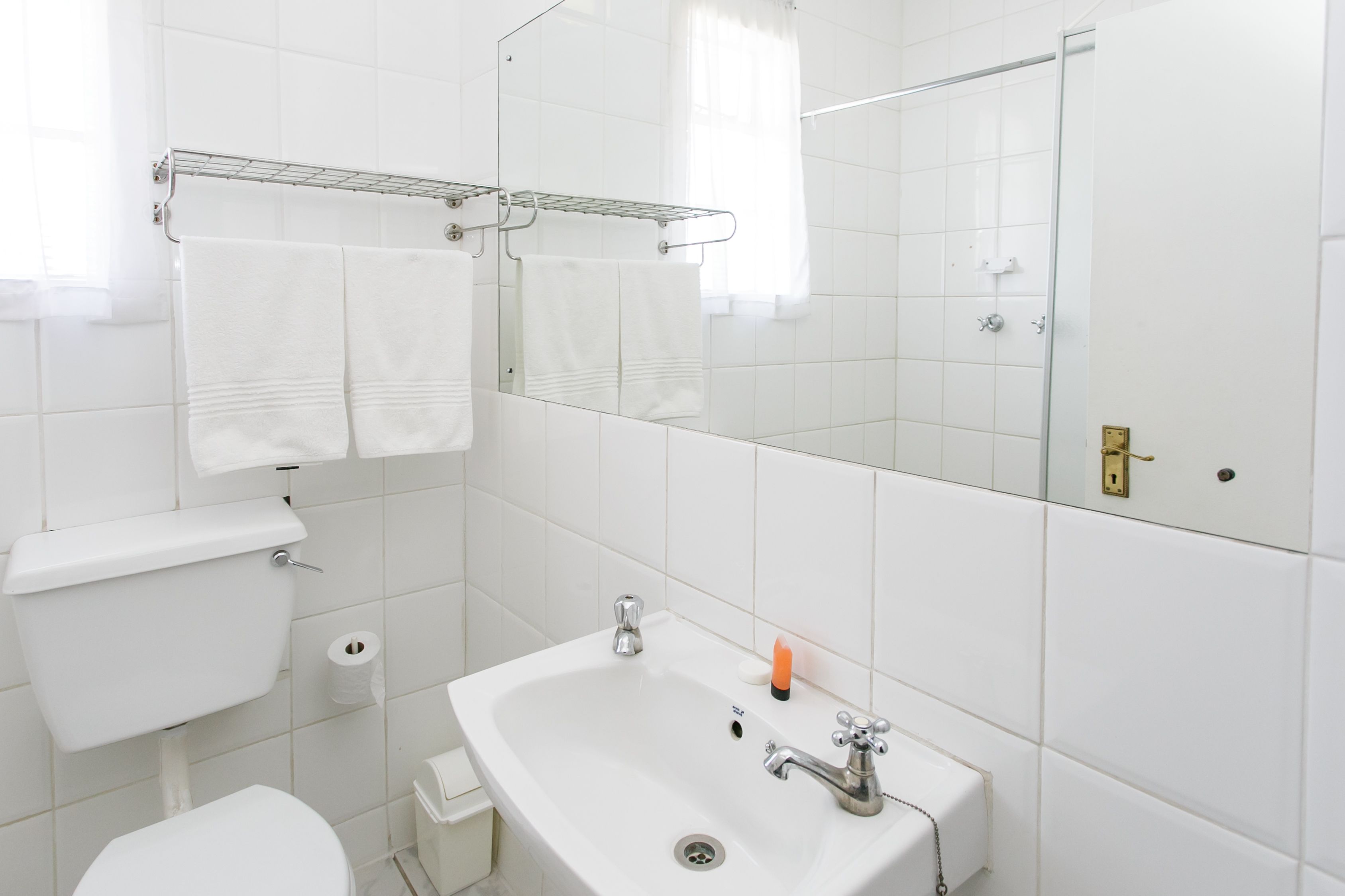 A bathroom with a toilet, sink, and mirror.