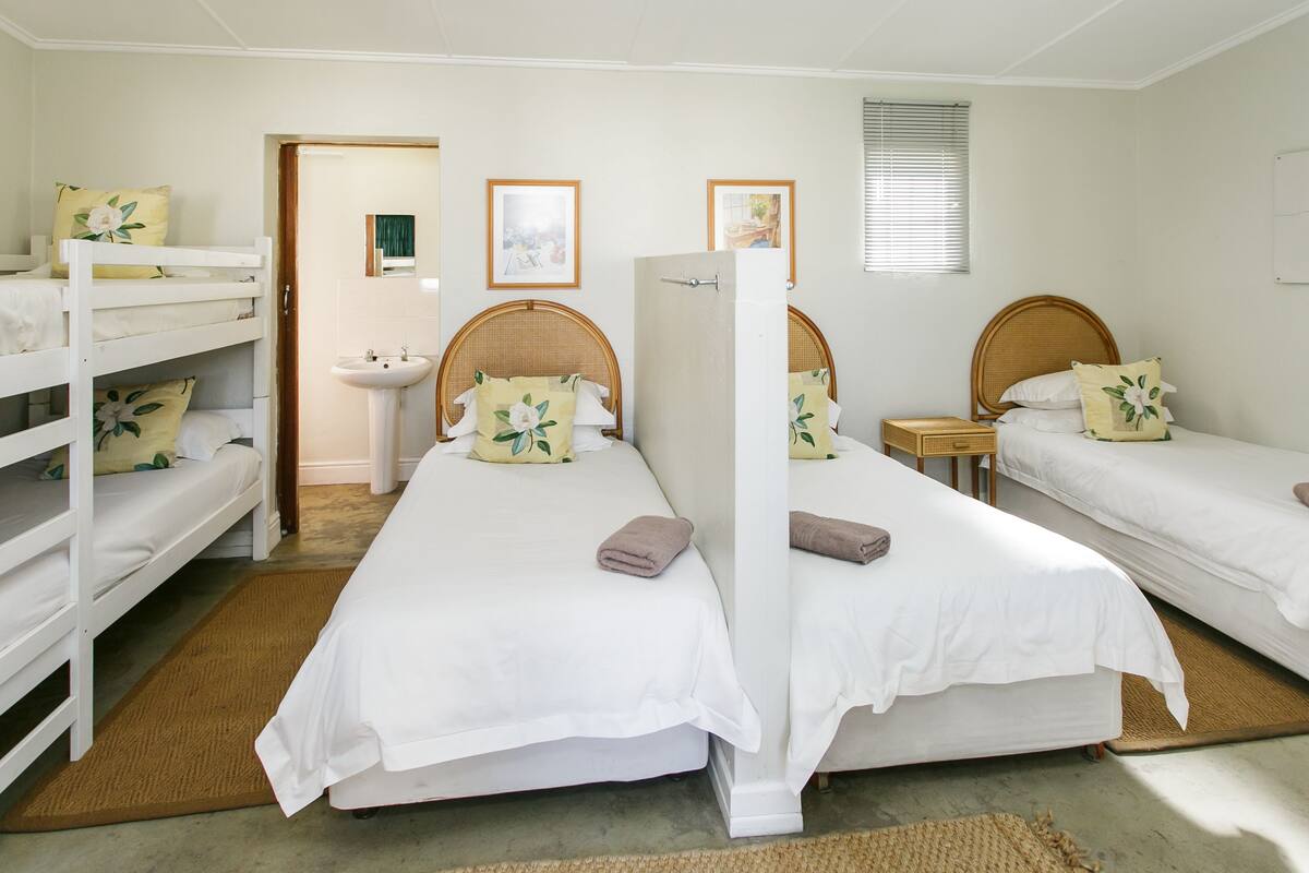 A room with bunk beds, a bedside table, a mirror, and a window.
