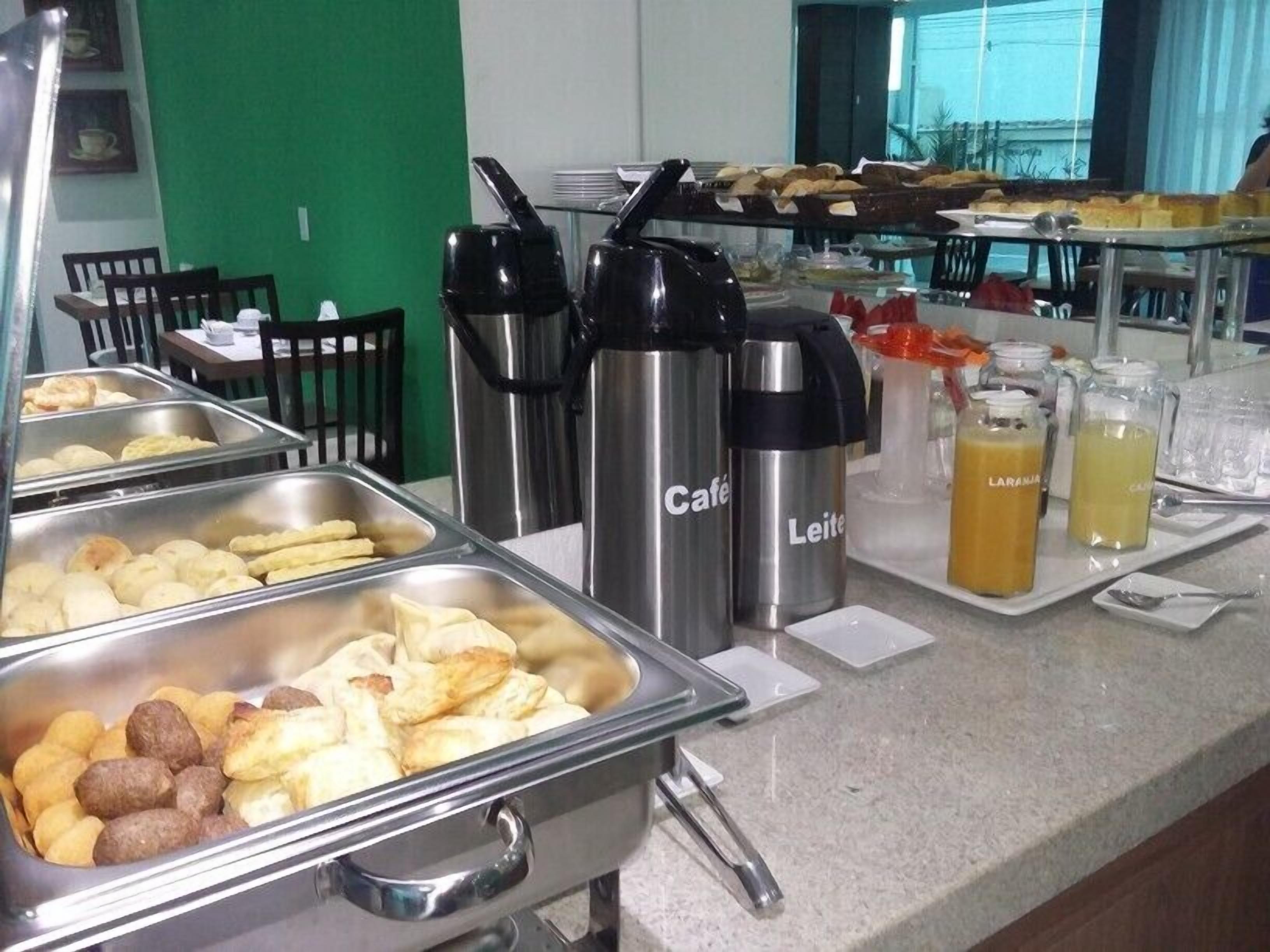 Un buffet con diversi cibi e bevande, tra cui una postazione caffè con tazze termiche a marchio.
